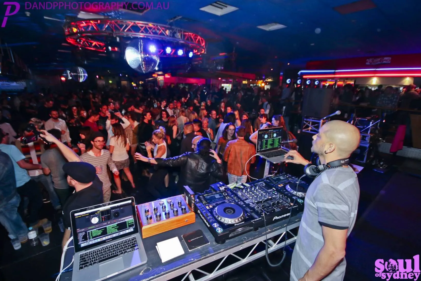 DJ CMAN DJing to a packed dancefloor at a Soul of Sydney club night, disco ball overhead