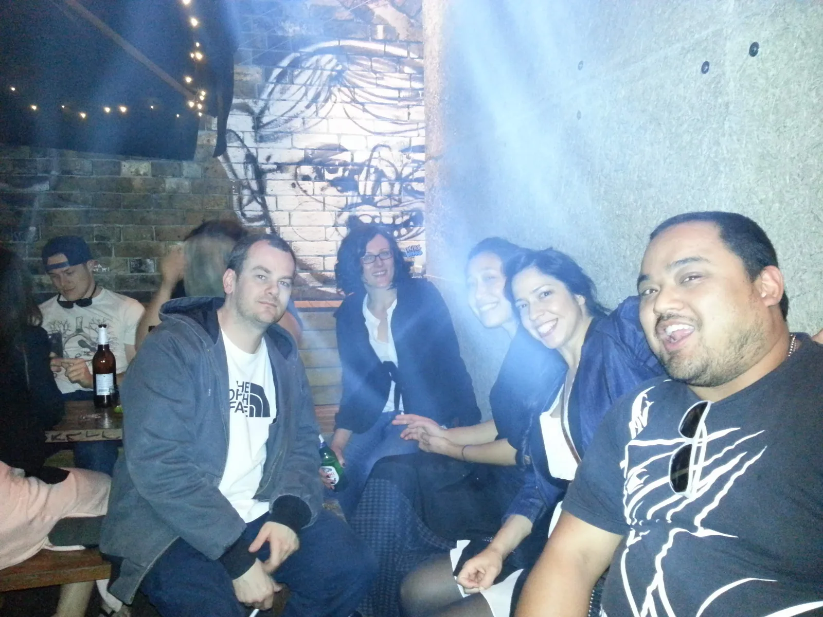 Group sitting together under a painted mural at Ching-a-Lings Sunday Sessions