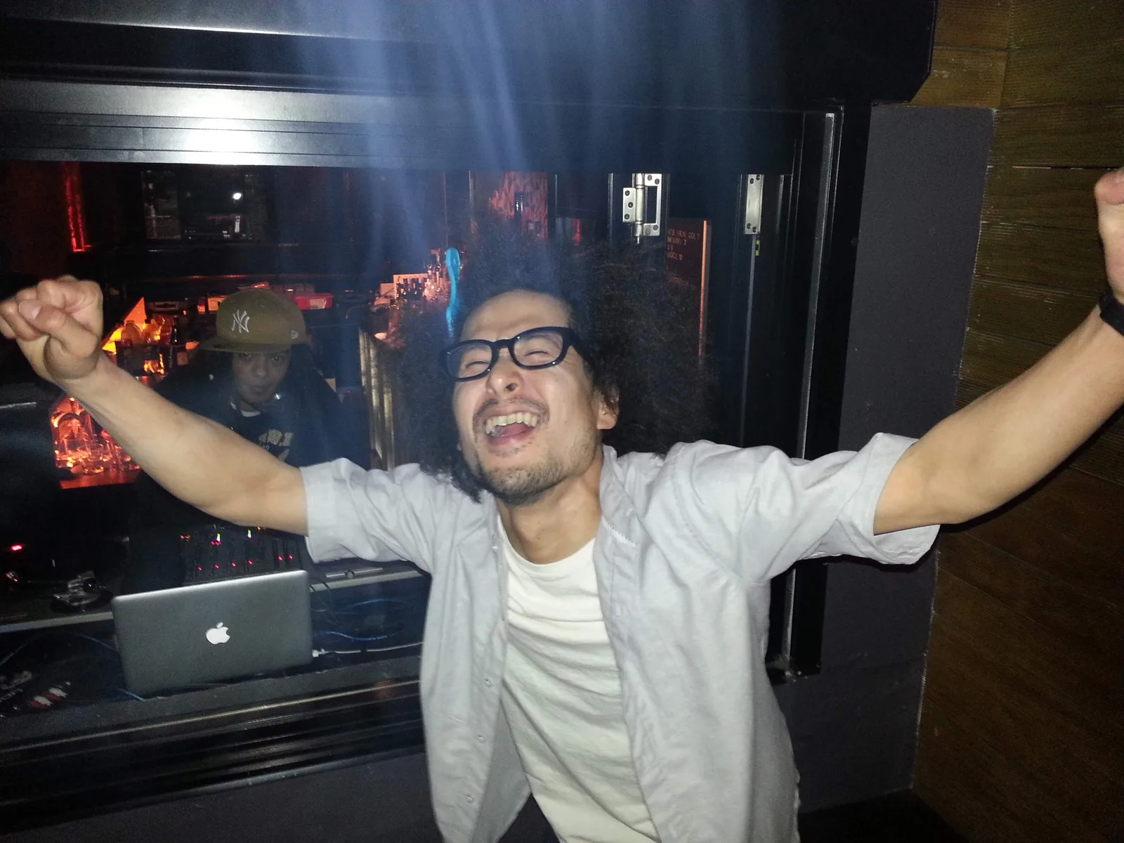 Someone with both arms raised beside the DJ booth at Ching-a-Lings
