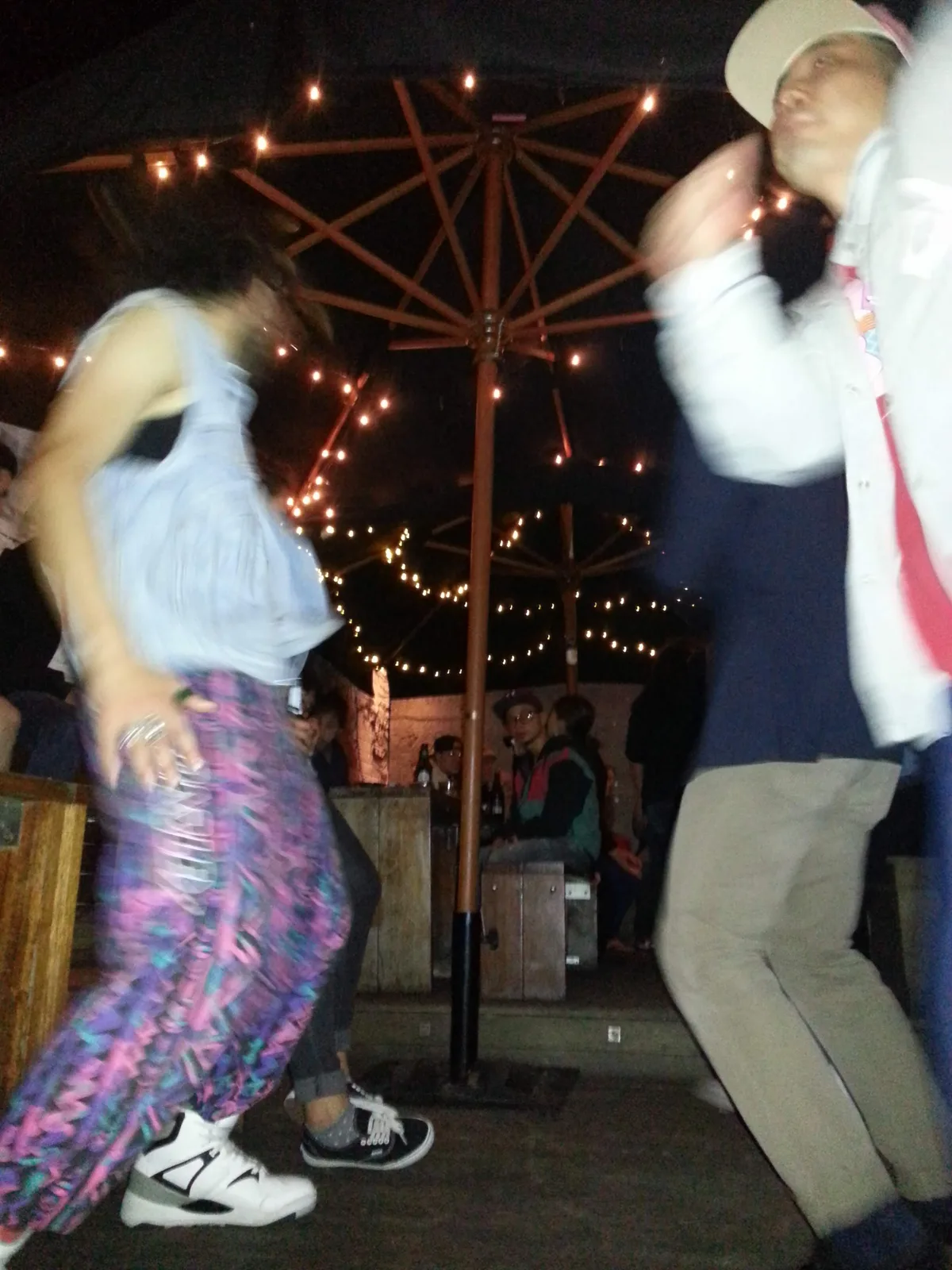 Two people dancing under an umbrella and string lights at Ching-a-Lings