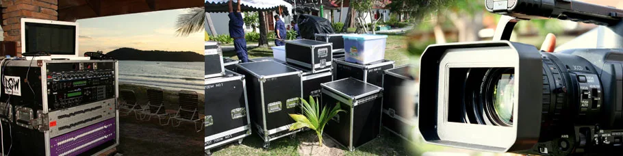 A wide banner strip of festival gear, flight cases and palm trees beside a camera lens