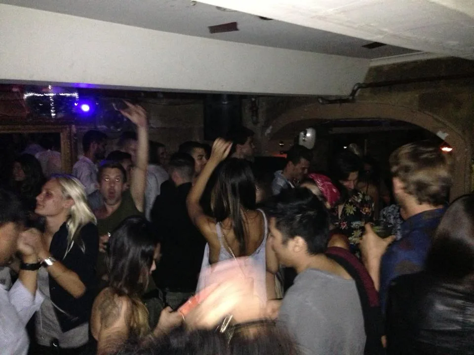 A crowded dancefloor at the Tatler with hands in the air under low light