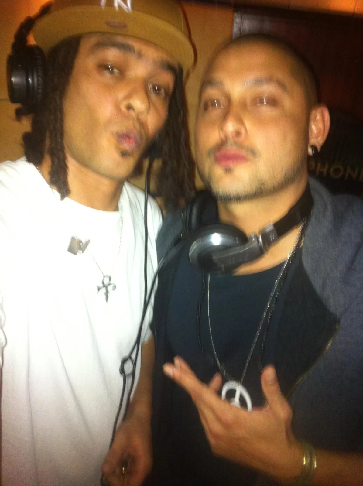 DJ CMAN and JuzzLikeDat squeezed into the booth for a portrait, headphones round both necks.