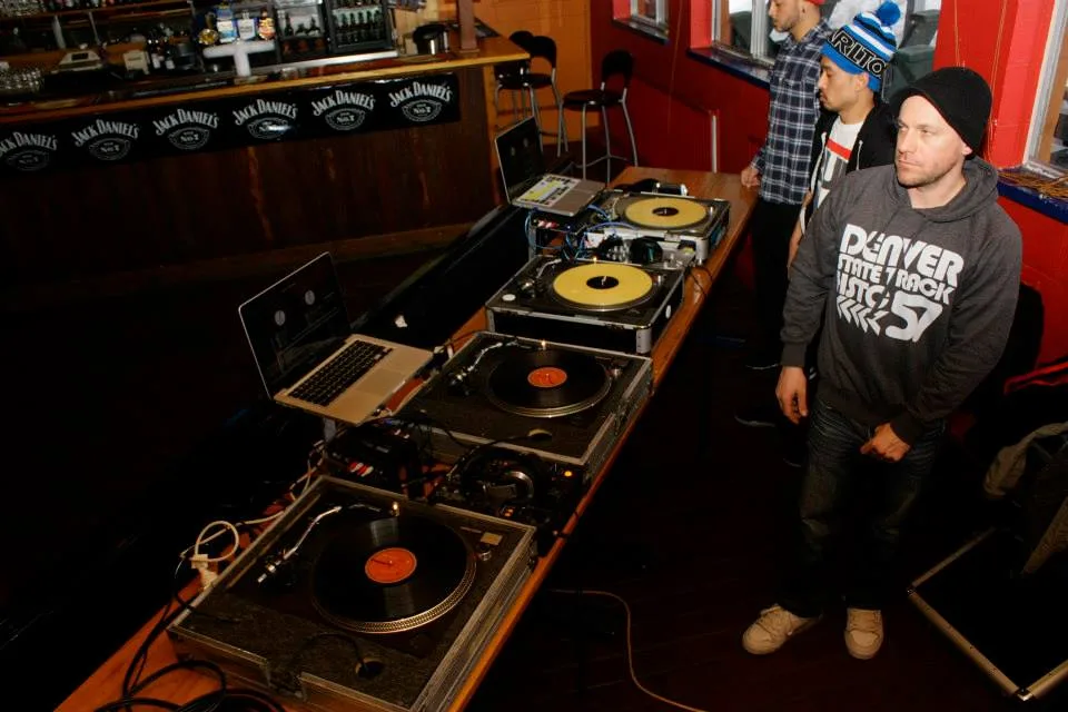 A DJ leaning into the mixer with the crowd pressed up against the booth