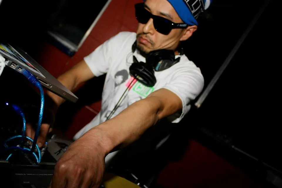 A DJ in a cap and sunglasses working the decks at the Fyve Funk Fire Snow Jam