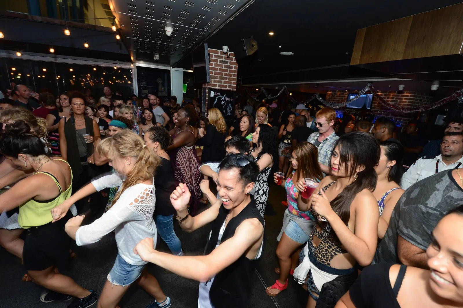 A wide view across the block party dancefloor, hands and heads in motion