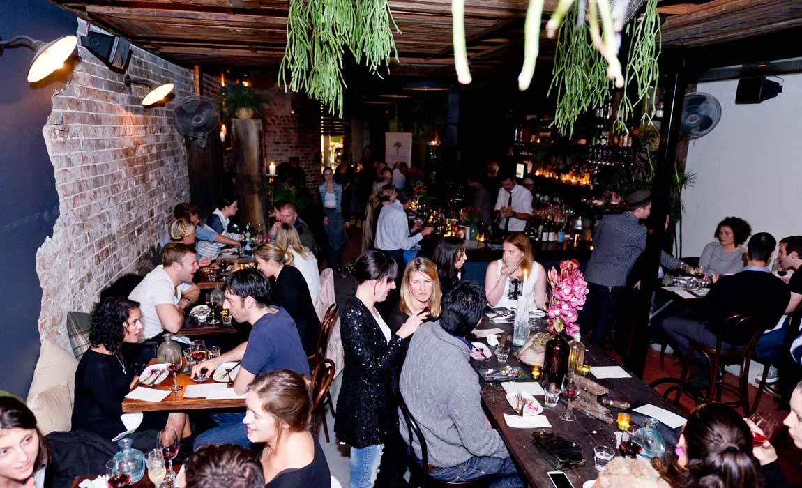 The interior of Bondi Hardware, long share tables and warm lighting