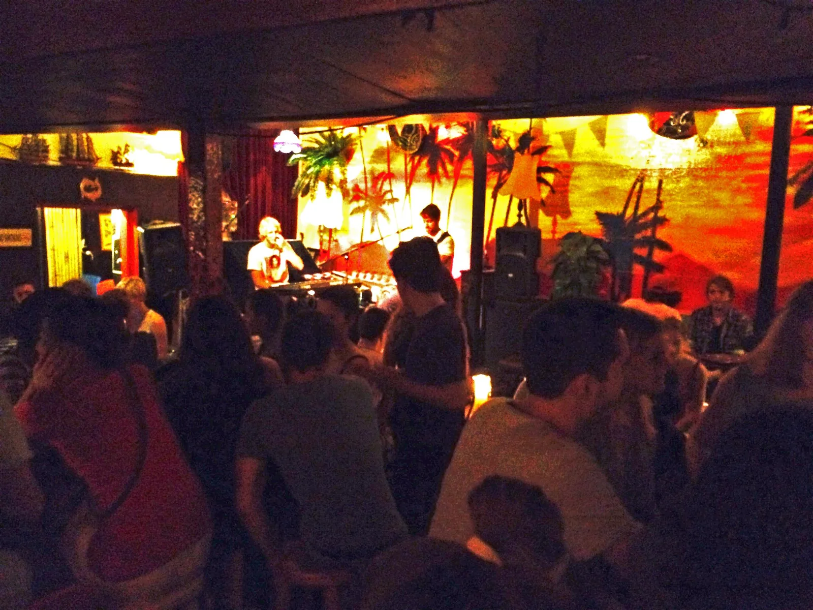 A band playing to a full room at Cafe Lounge, Surry Hills, in front of the painted sunset palm mural
