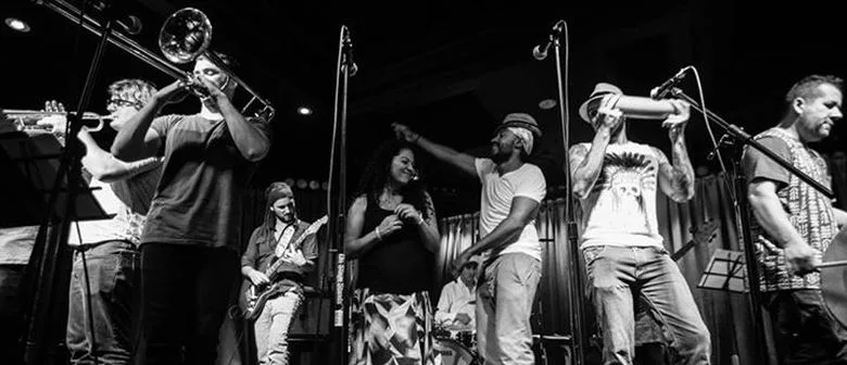 Cumbiamuffin's horn section, guitarist and singers across the stage, black and white