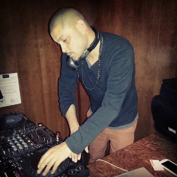 DJ CMAN at the decks during the Grain Bar residency, Four Seasons Hotel Sydney, headphones around the neck
