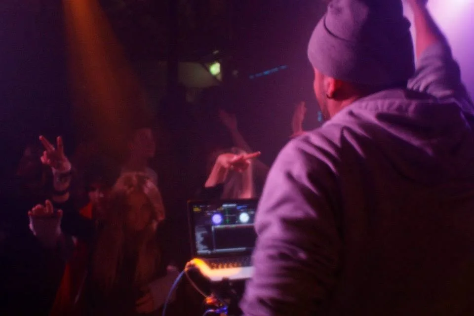 A DJ cueing a record behind the decks in a darkened room