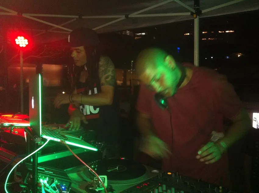 A DJ at the decks under red light at the Greenwood Hotel