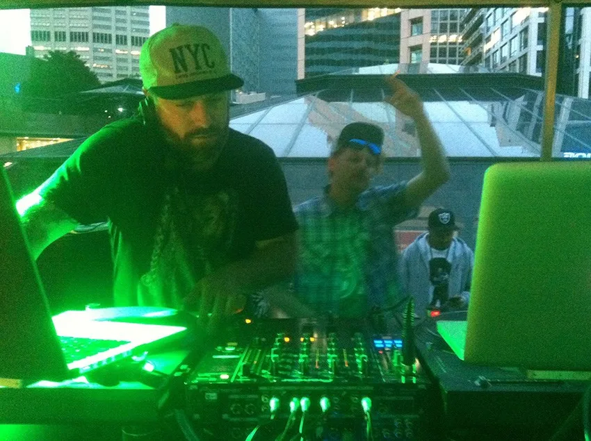 A DJ mid-set with stage lights washing over the booth