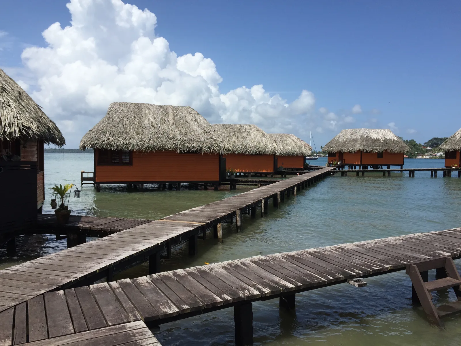 Overwater bungalows along a timber jetty on calm water
