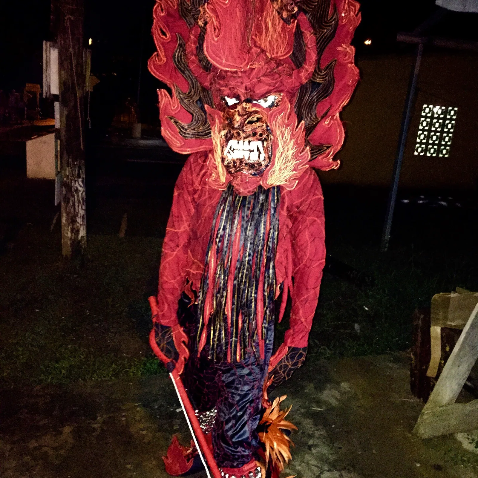 A performer in an elaborate red devil costume at a street festival
