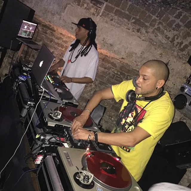 DJ CMAN in a yellow tee working the turntables