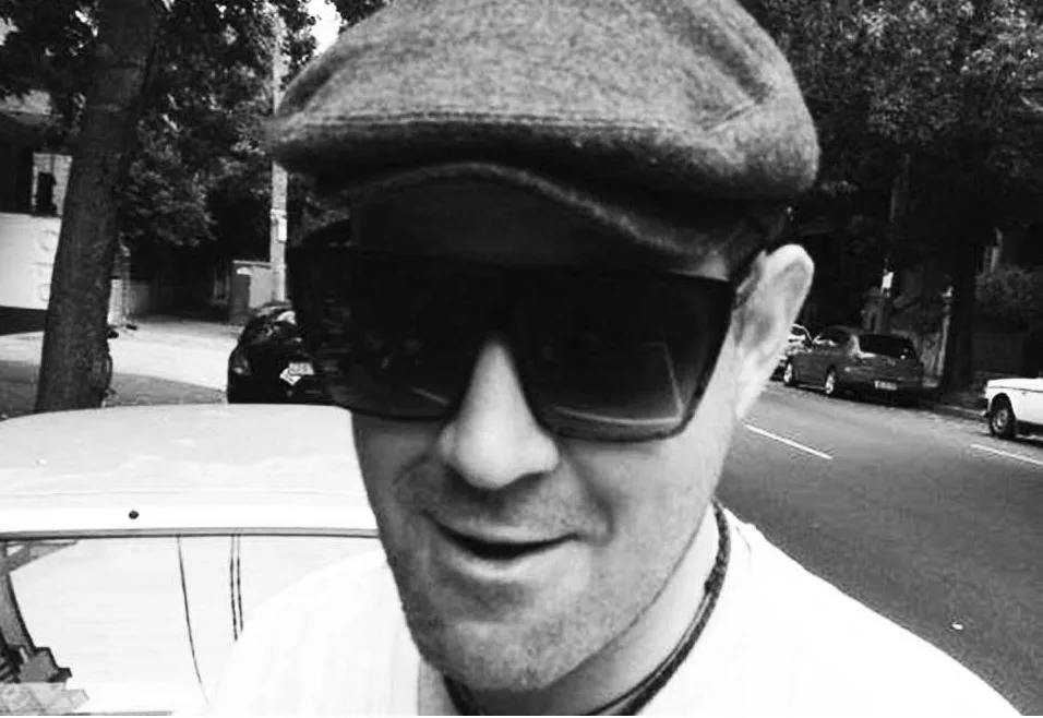 A black and white portrait of a DJ in a flat cap