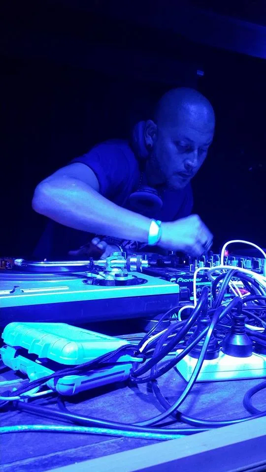A DJ working the decks under blue light at the Jam Gallery