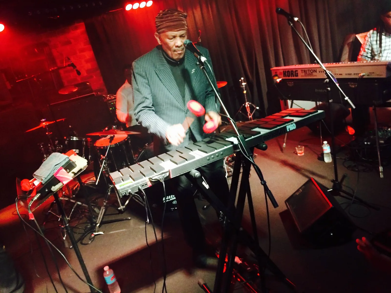 A musician playing keys on stage under red light