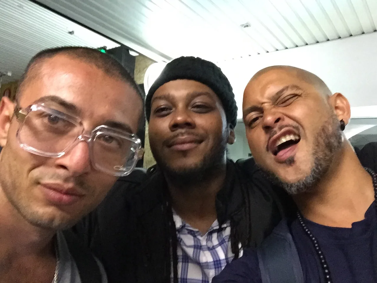 Three DJs crowded together laughing for a photo at the Jam Gallery