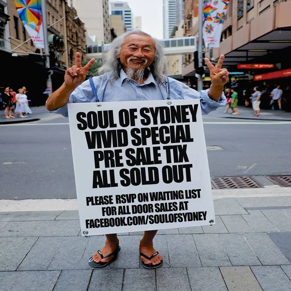 A man holding up a hand-made sign saying the Soul of Sydney Vivid special pre-sale tickets are sold out
