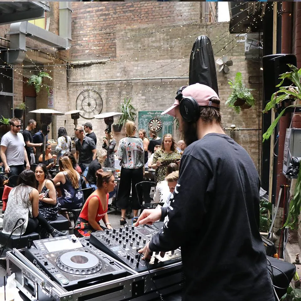 A courtyard crowd around the DJ booth at Beats n Brunch