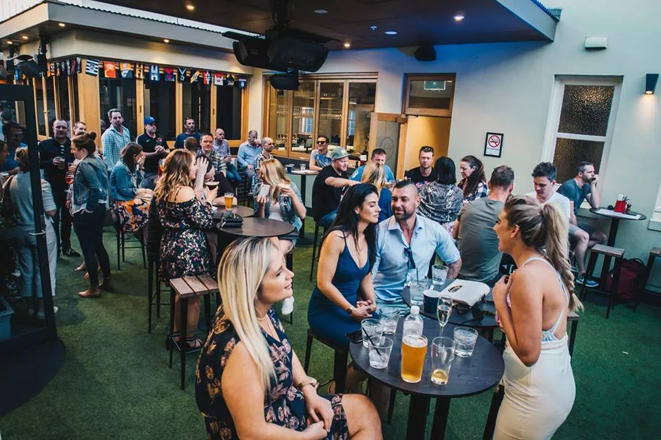 An outdoor crowd with drinks in hand at Goros