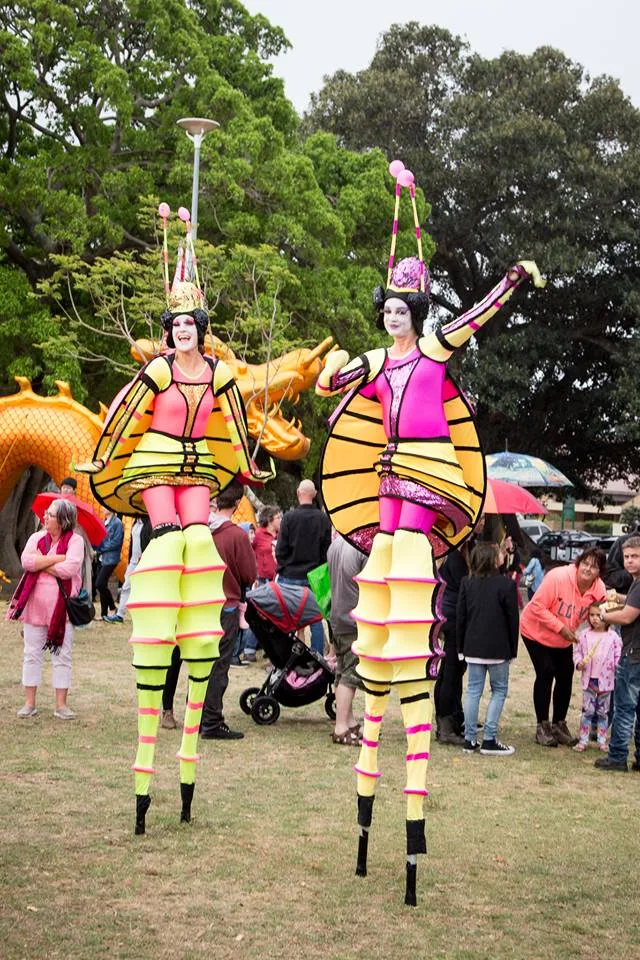 Stilt walkers in costume moving through the street festival crowd