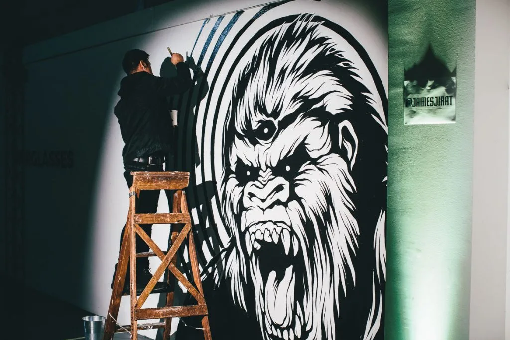 An artist on a ladder working on the gorilla mural
