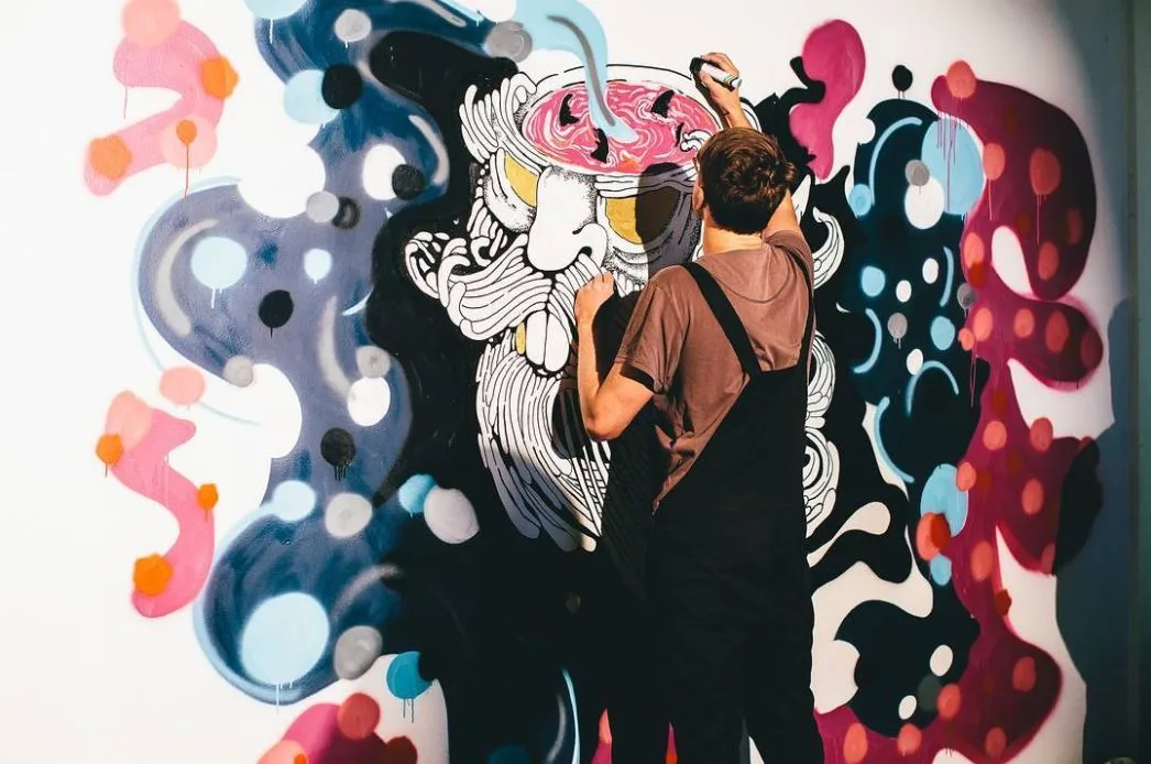 A colourful street art mural part way through being painted