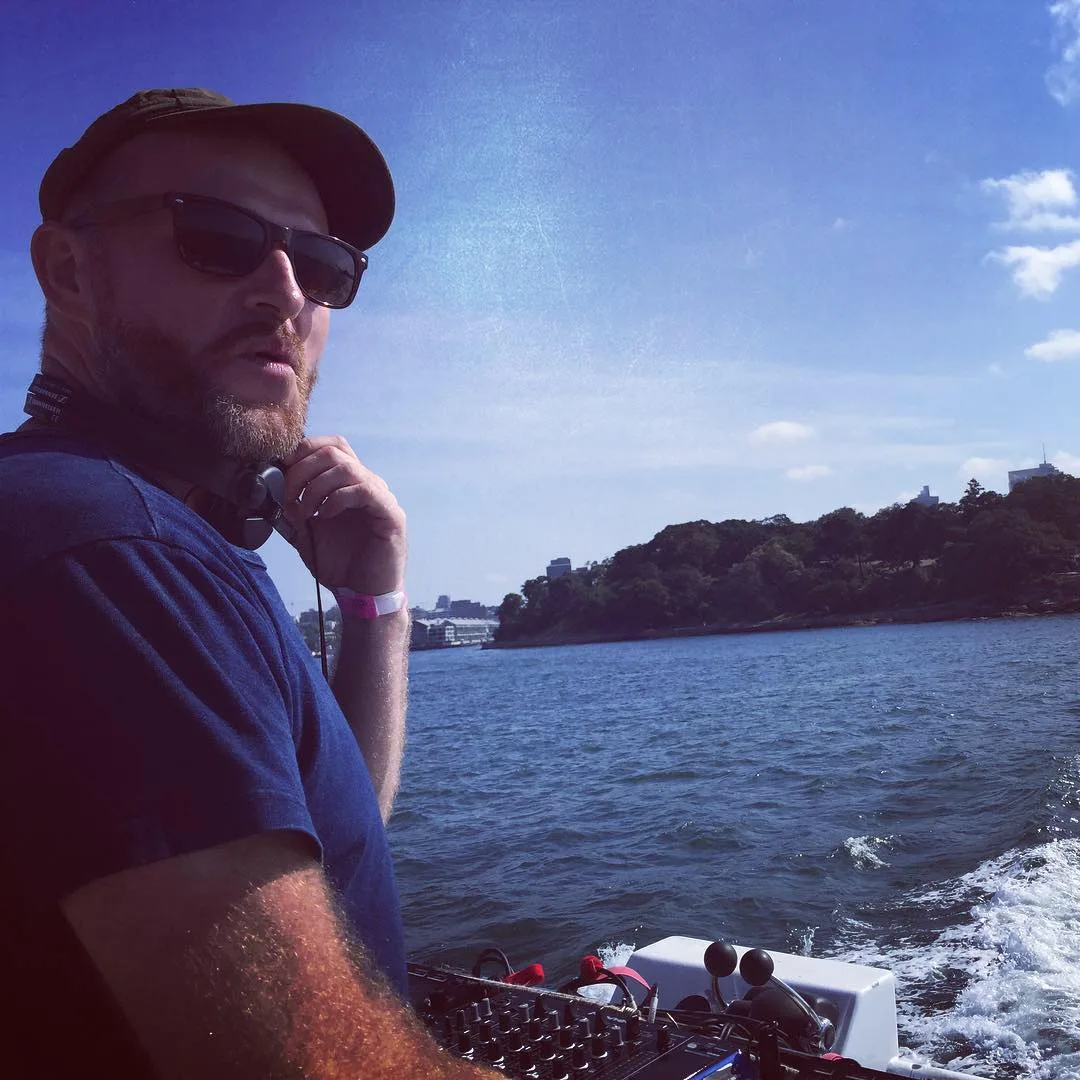 A man on the deck of a boat out on the harbour