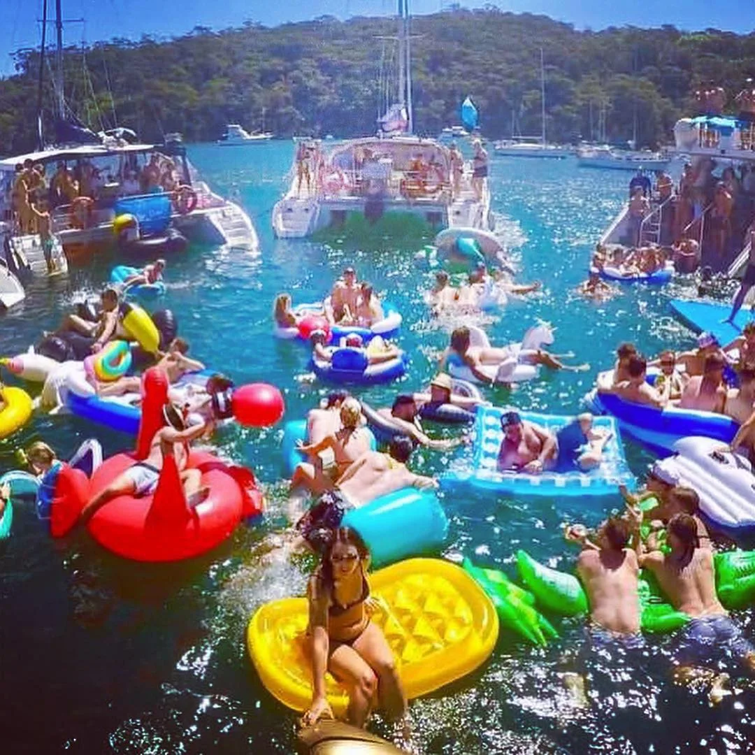 Swimmers and inflatables packed together between the boats