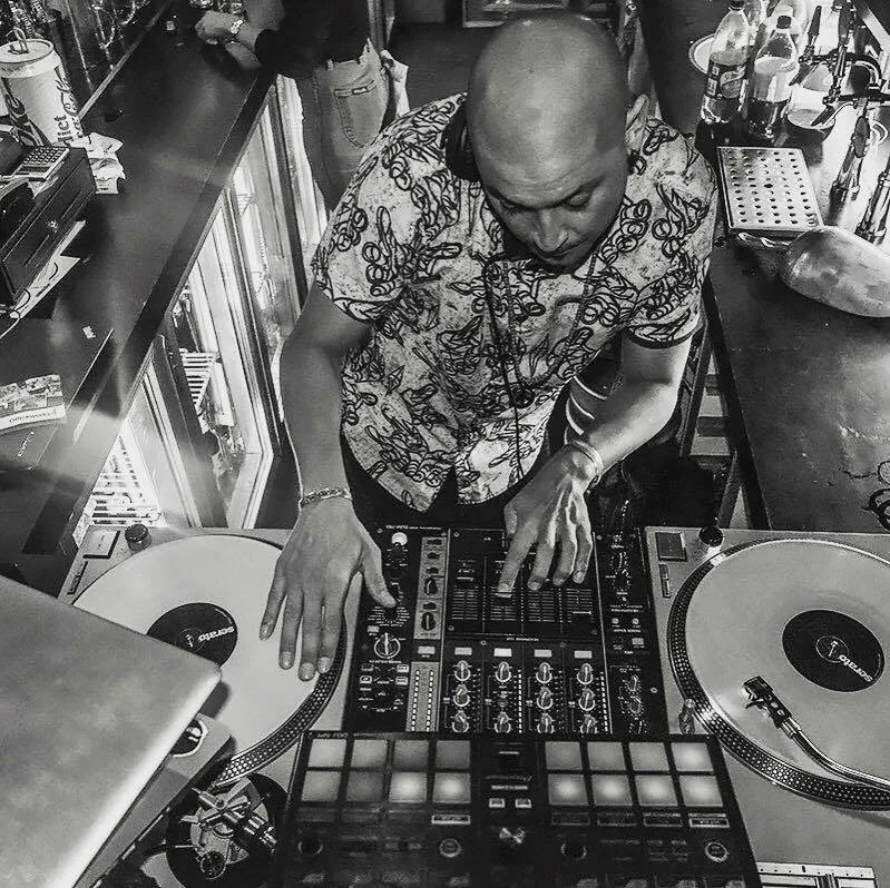 DJ CMAN mixing on two turntables, seen from overhead, black and white