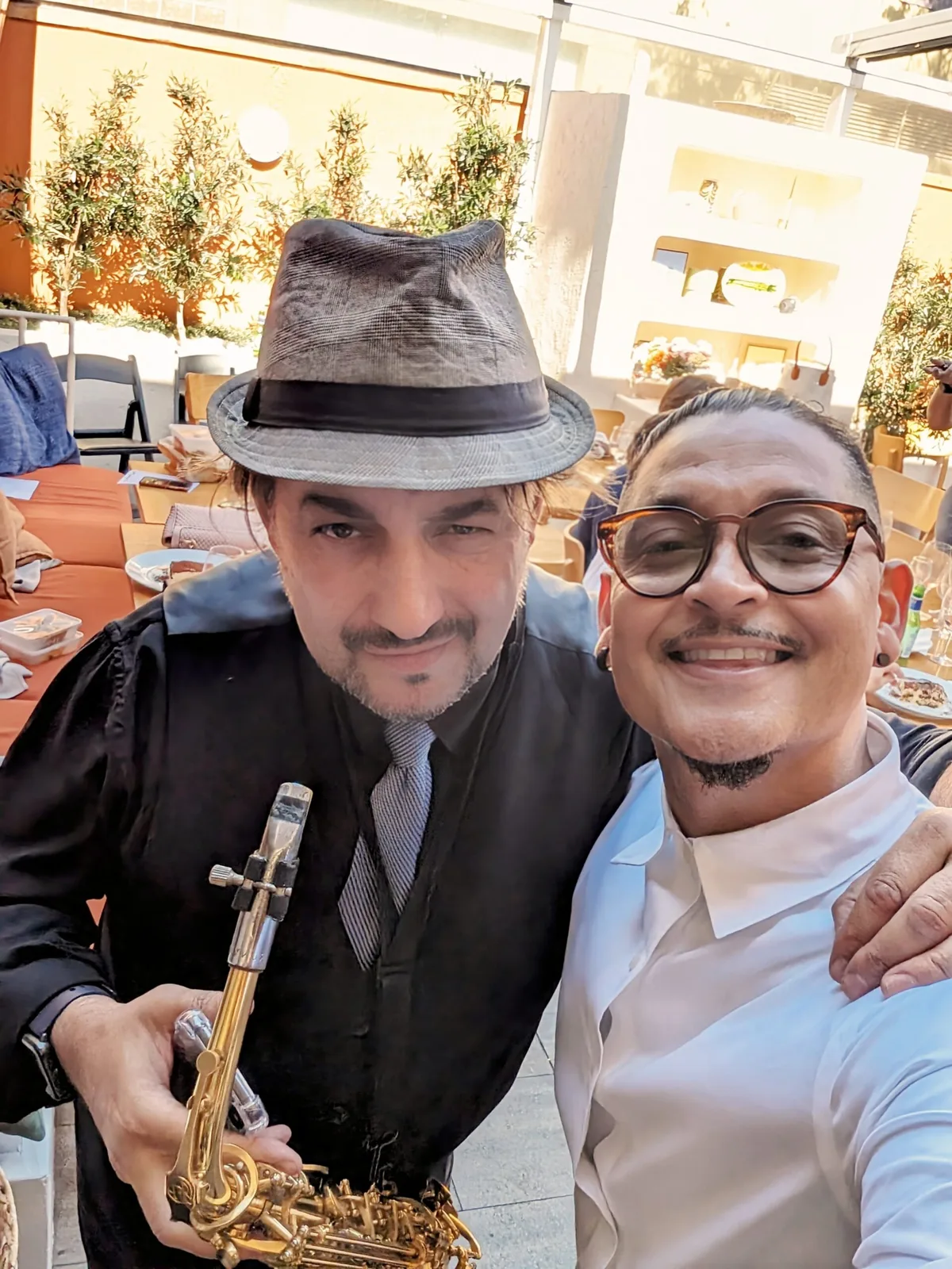 A selfie of two men at a venue, one in a hat