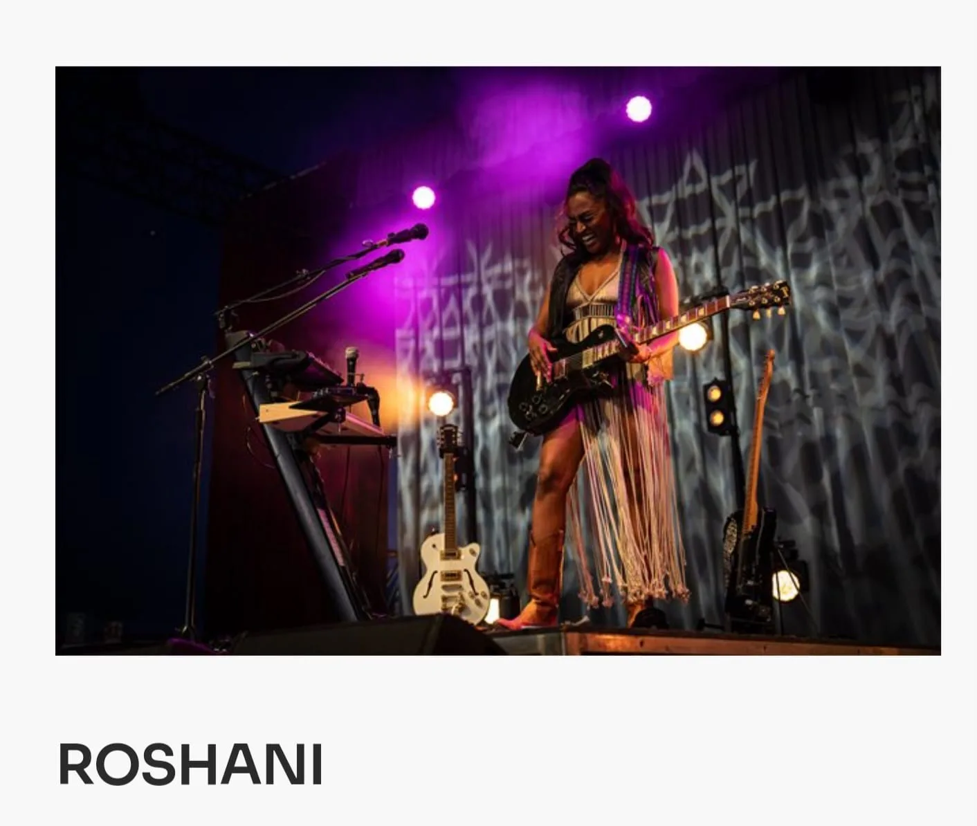Roshani performing live on stage under purple light