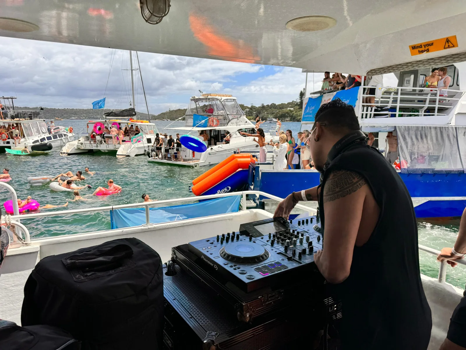 A DJ playing on deck with boats rafted up alongside