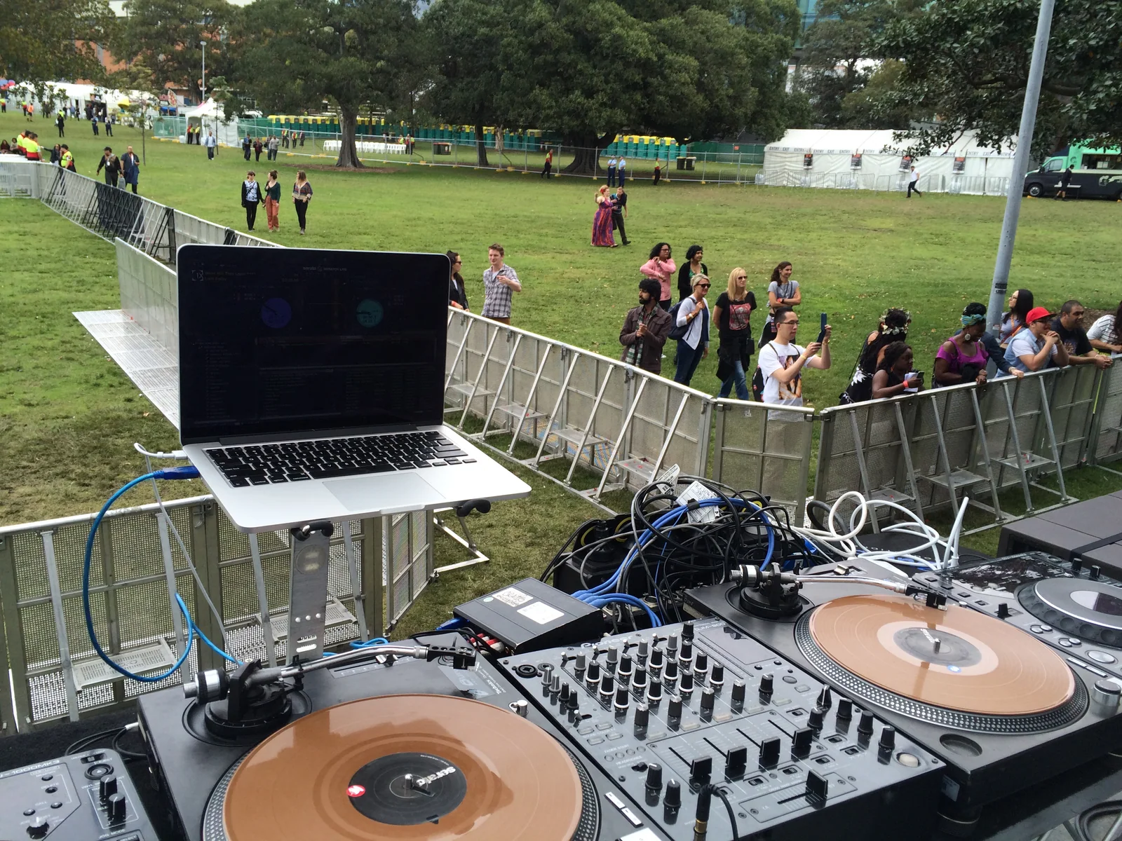 Turntables, mixer and a laptop in the DJ booth at morning soundcheck, first punters wandering into Victoria Park behind the barrier