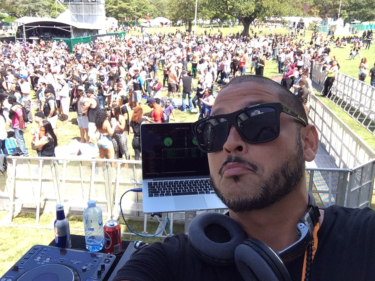 CMAN selfie in sunglasses at the decks, headphones round his neck and the Victoria Park festival crowd behind