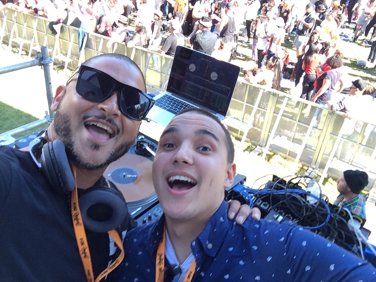 CMAN and DJ Trey grinning into a selfie at the decks with the festival crowd spread out behind them